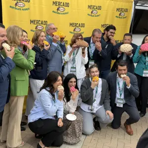 The Gonzalez family and local dignitaries with "The First Bite" to open the store, using a concha, or Mexican sweet bread.