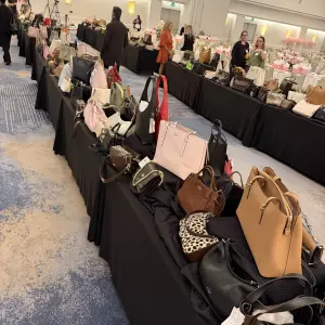 Guests walk around the displayed purses looking for the one they want